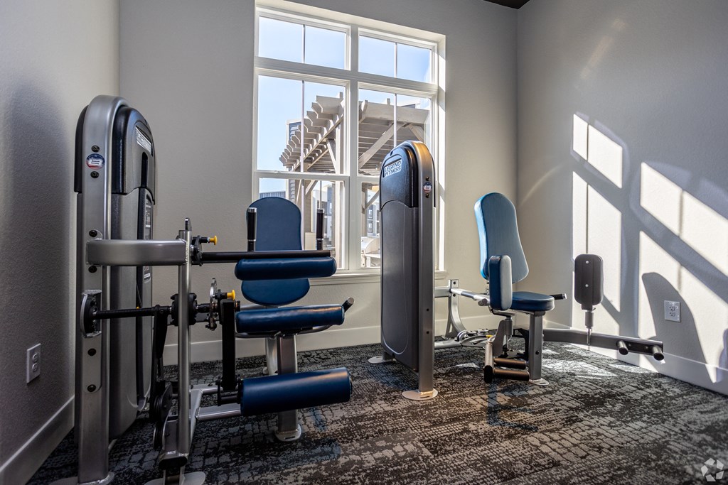 A gym room with a rowing machine, a bench, and a chair.