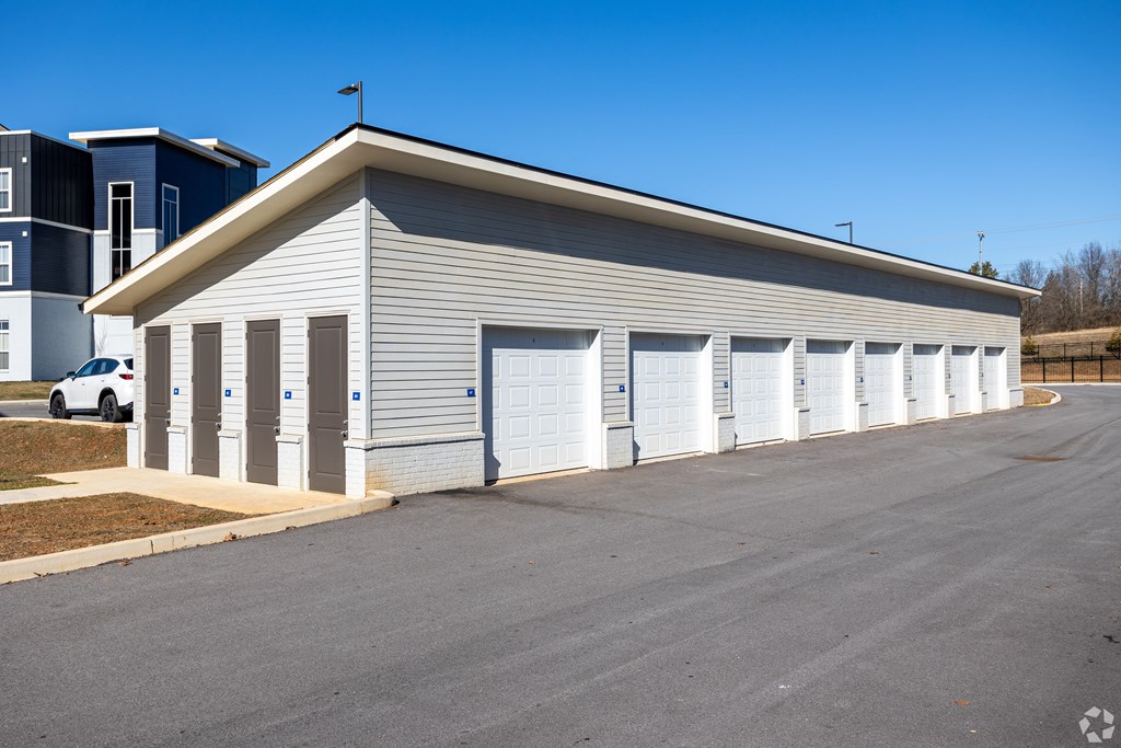A long building with a grey roof and white garage doors.