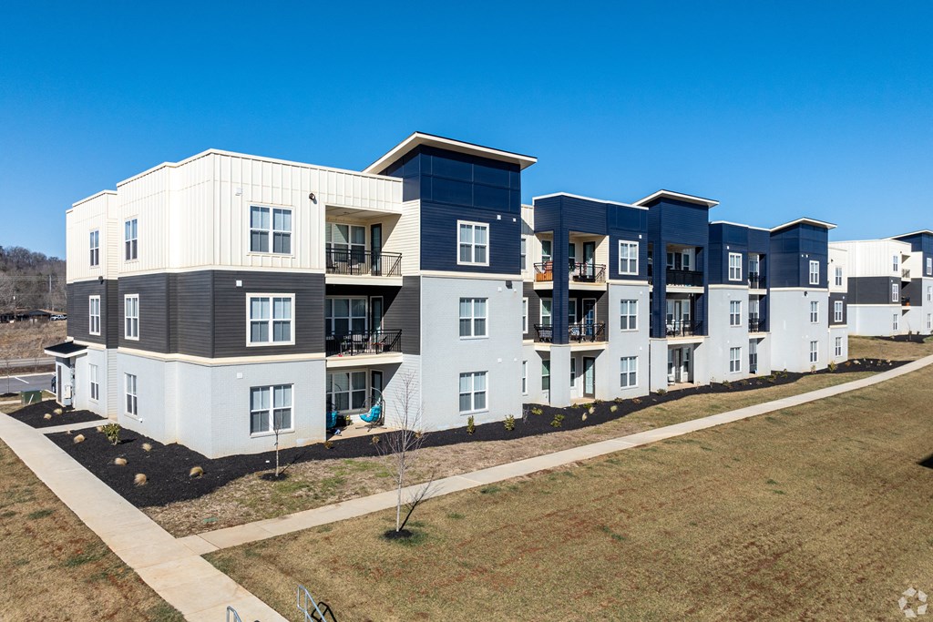 A row of modern townhouses with balconies and a clear blue sky above.