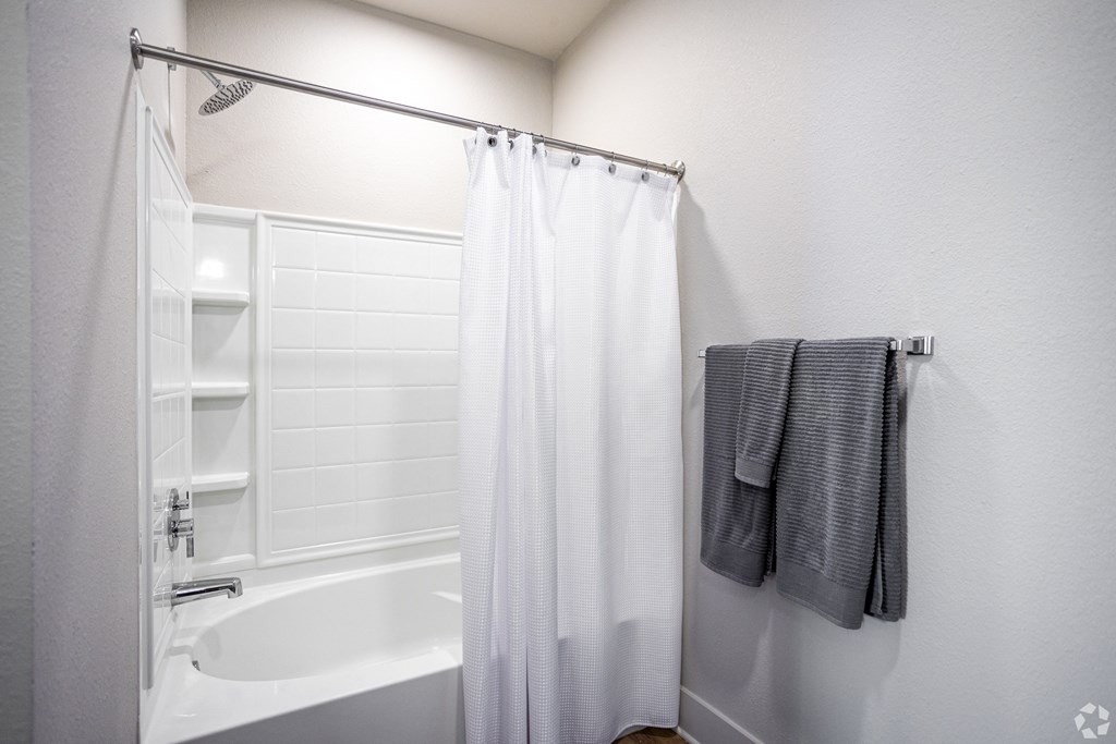 A white bathroom with a white tub and a white shower curtain.
