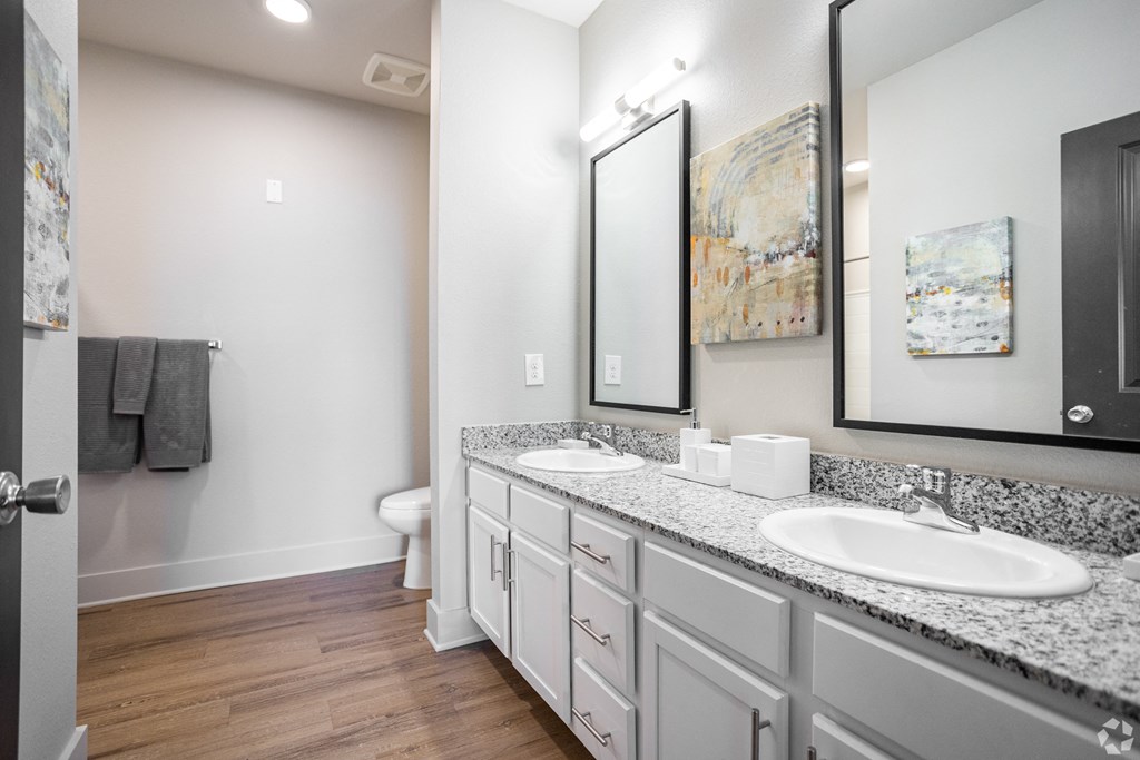 A bathroom with a toilet, sink, and mirror.