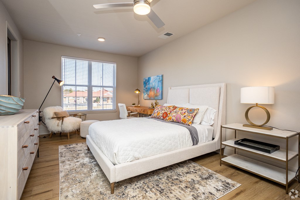 A bedroom with a white bed, a white dresser, and a white rug.