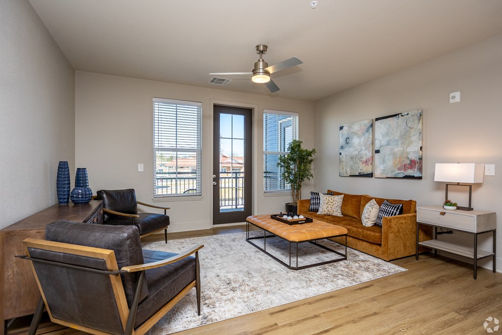 A living room with a brown sofa, a black chair, a coffee table, and a painting on the wall.