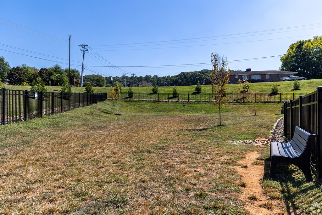 A park with a bench and a fence.