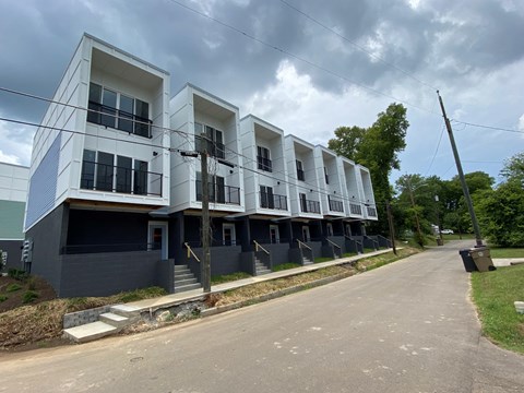 a row of white and blue apartment buildings with a road in front