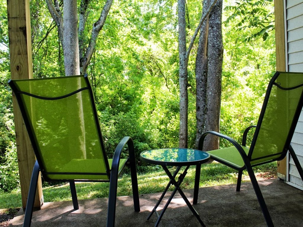 two chairs and a table on a porch with trees