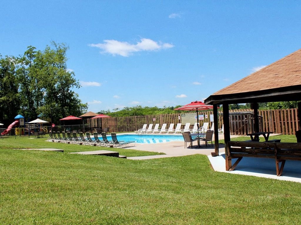 a swimming pool with chairs and a pavilion