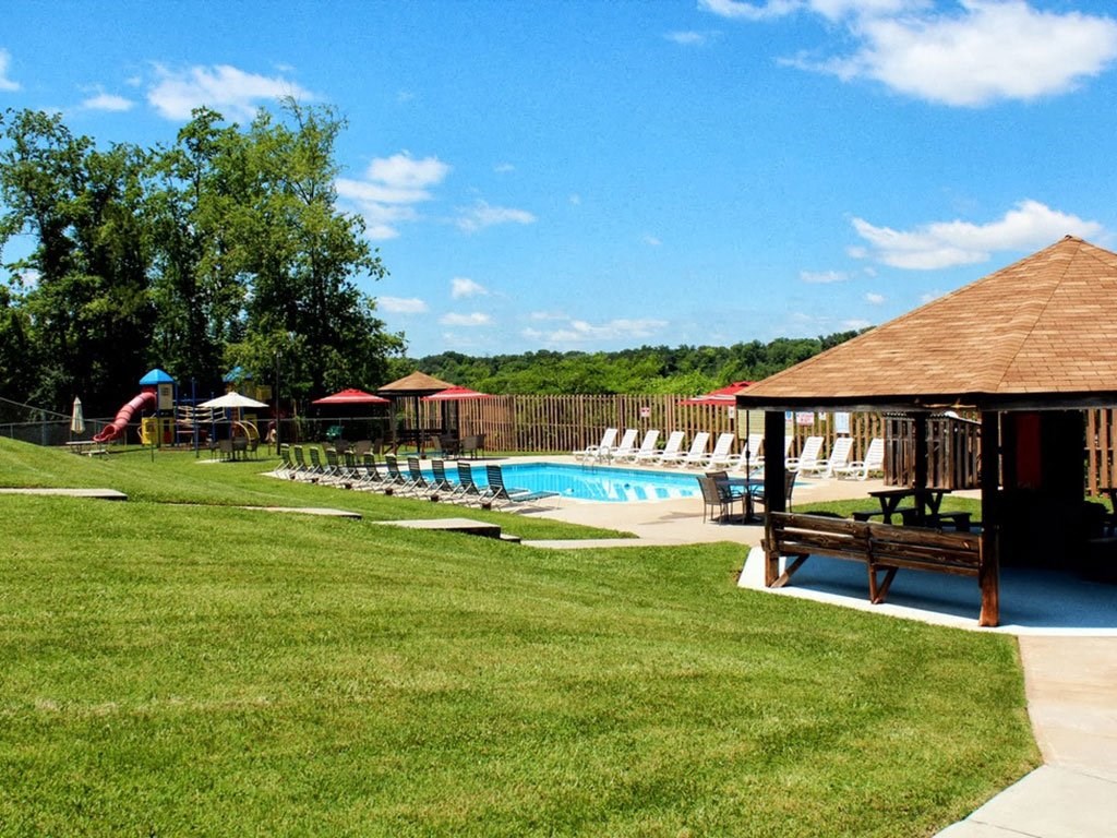 a pool with chairs and a gazebo in the grass