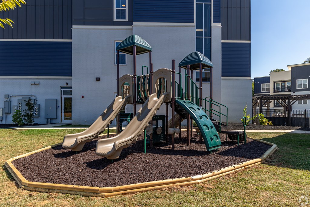 A playground with a green slide and a brown sandbox.