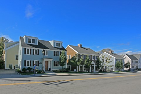 A row of houses with a man walking in front of the first house.