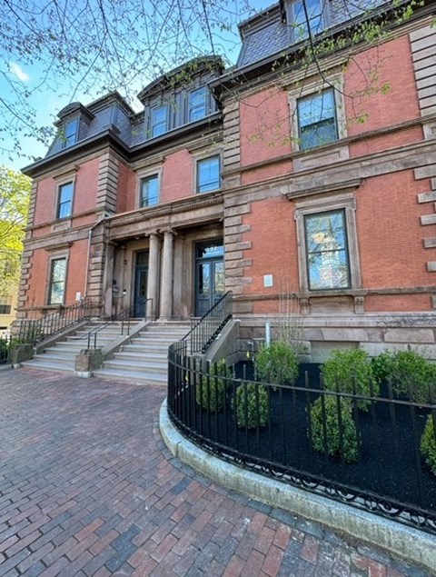 A red brick building with a black iron fence and a black gate.