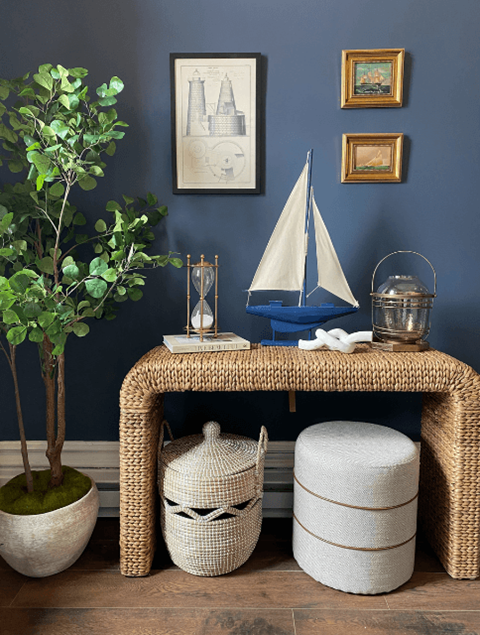 a wicker bench with a sailboat and baskets in a blue walled room