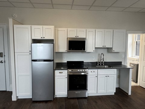 A kitchen with white cabinets and a black countertop.