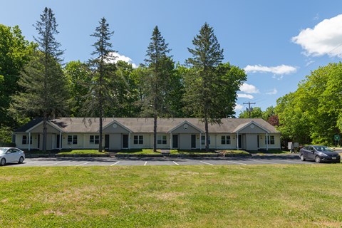 a home with a parking lot and trees in the background
