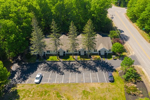 arial view of a house with a parking lot and trees