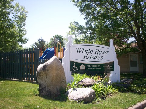 a white river estates sign in front of a playground and rocks