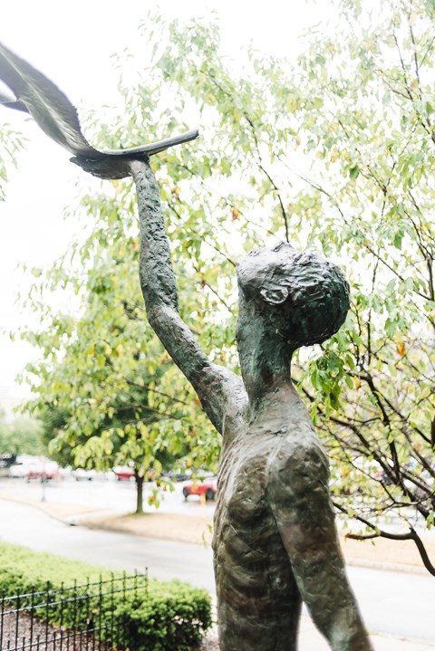 Statue in park area green trees