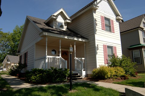 a white house with a white porch and a red door