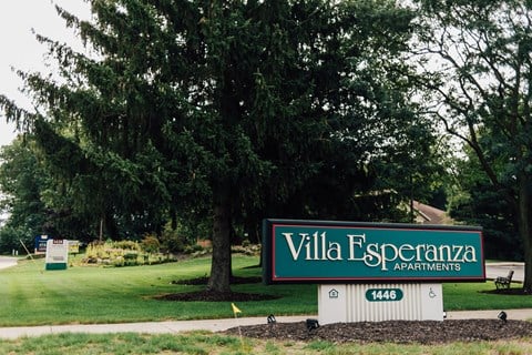 a sign for the villa esperanza apartments in front of a tree