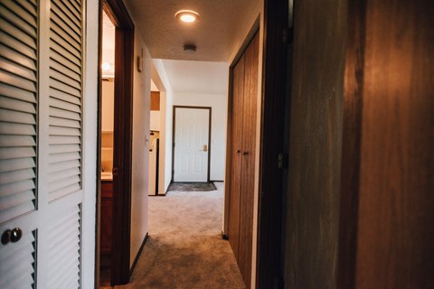 a hallway with wooden doors and a white door to a bedroom