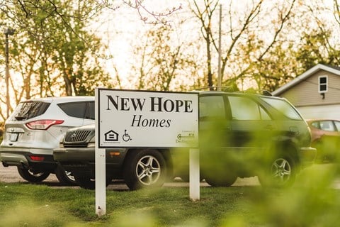 a sign for new hope homes in front of parked cars
