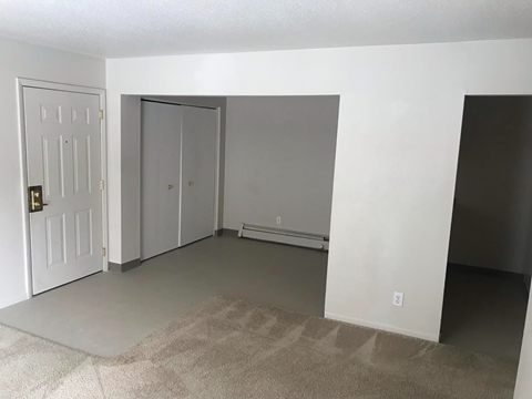 an empty living room with white walls and a door