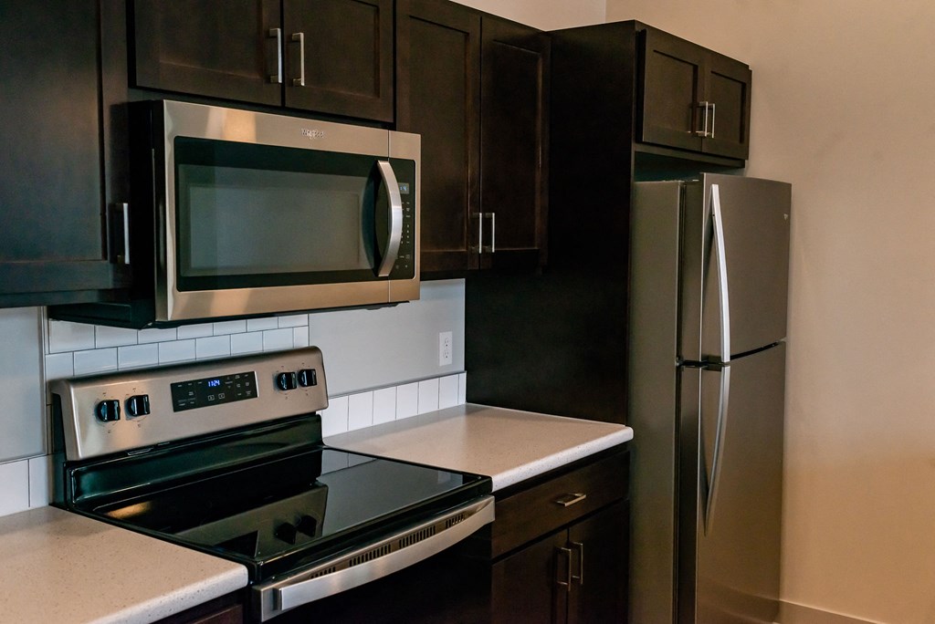modern kitchen with stainless steal appliances, dark cabinets and light countertops
