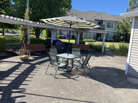A patio with a table and chairs under an umbrella.
