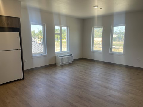 A kitchen with a white refrigerator and wooden floors.