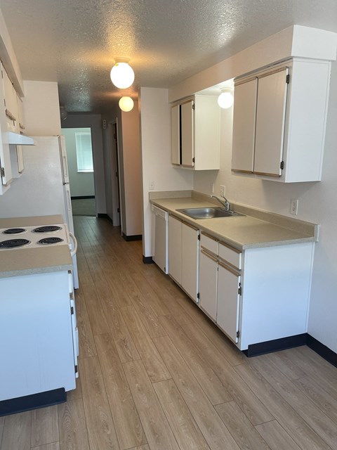 A kitchen with white appliances and wooden floors.