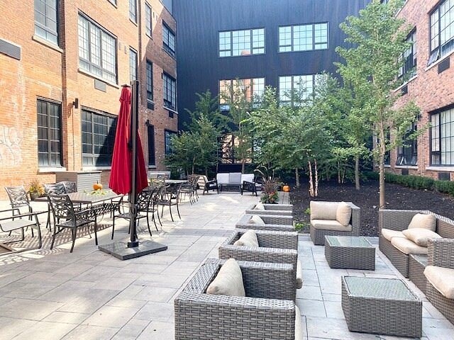 a courtyard with tables and chairs and a red umbrella