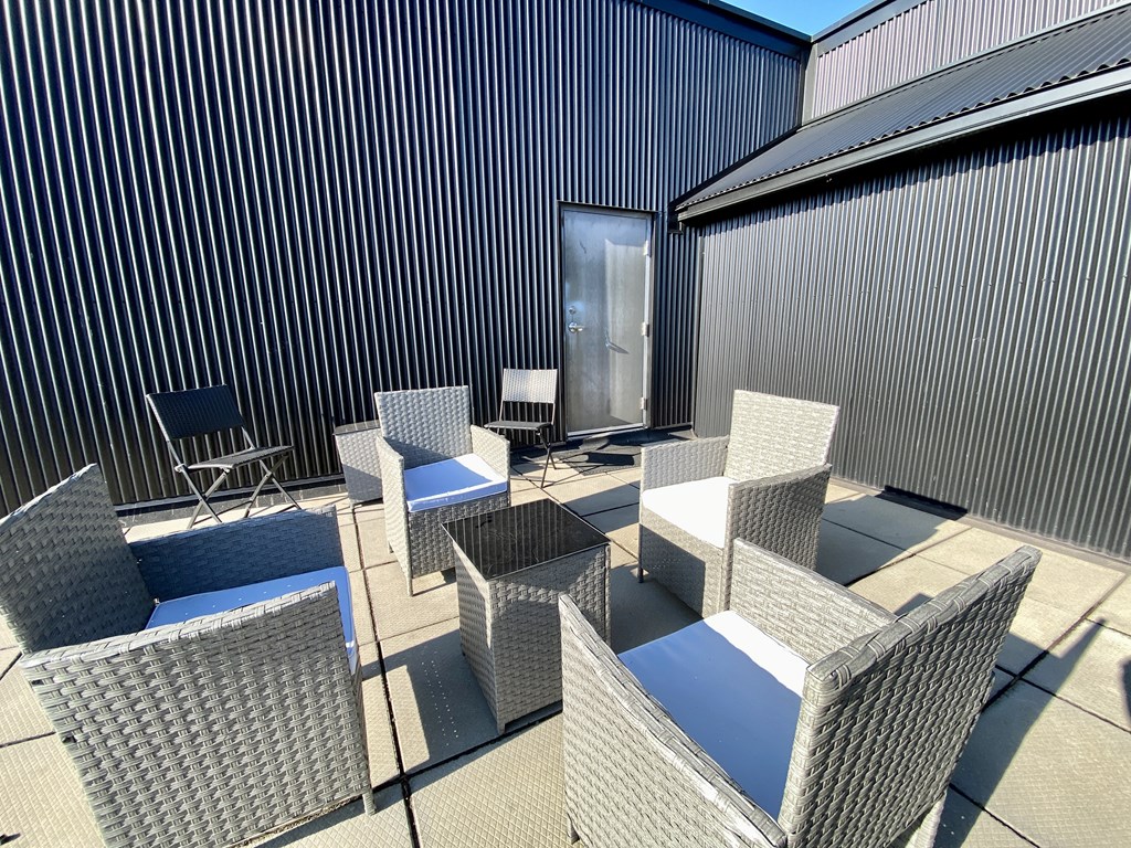 a patio with chairs and tables in front of a building