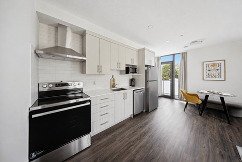 A modern kitchen with white cabinets, stainless steel appliances, and a black stove top oven.