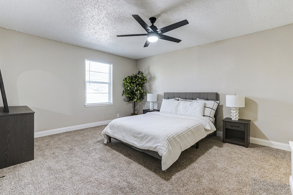 an empty bedroom with a bed and a ceiling fan