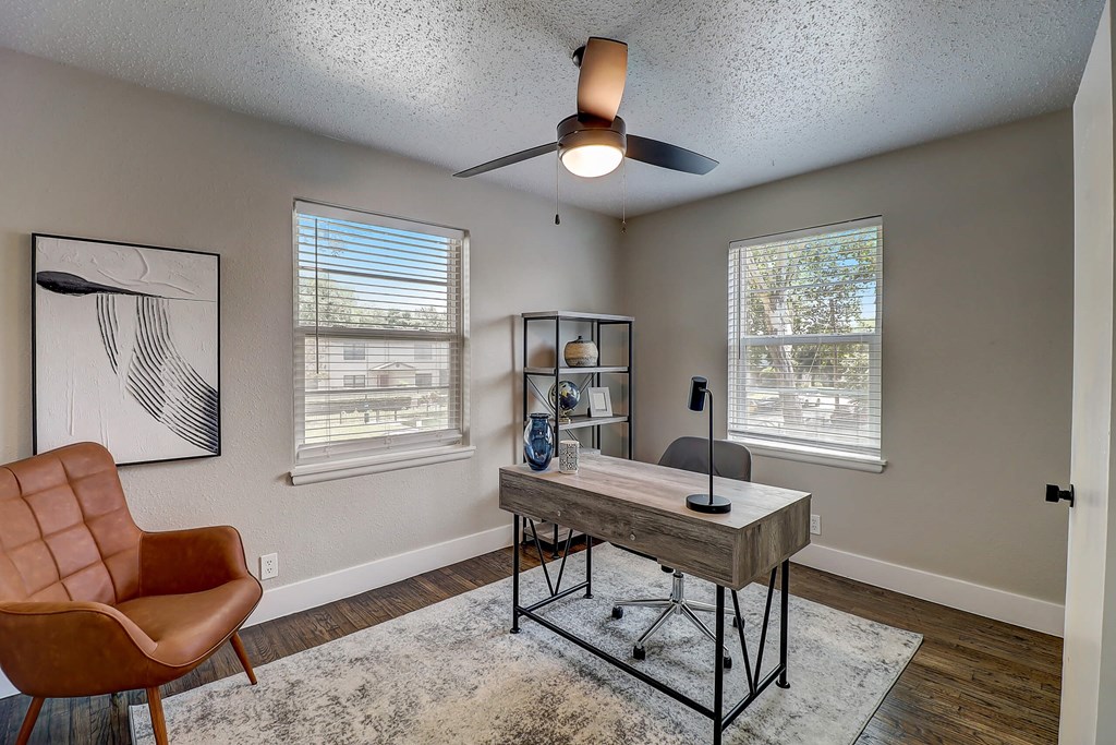 a home office with a desk and a ceiling fan