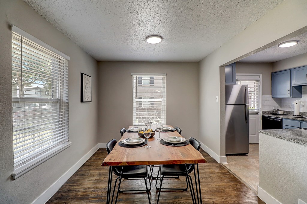 a dining room with a wooden table and chairs and a kitchen with stainless steel appliances