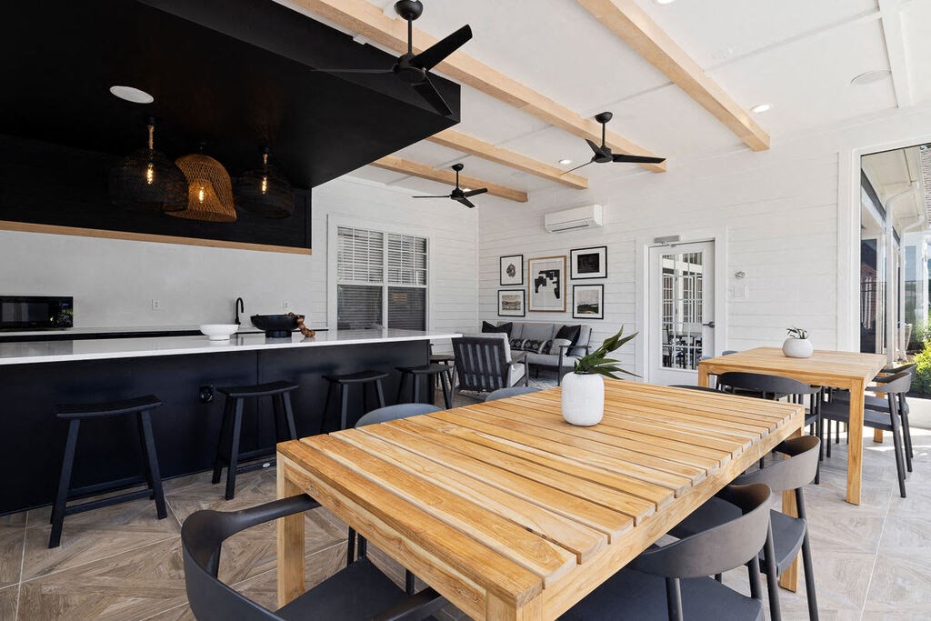 a dining area with a wooden table and chairs and a kitchen in the background