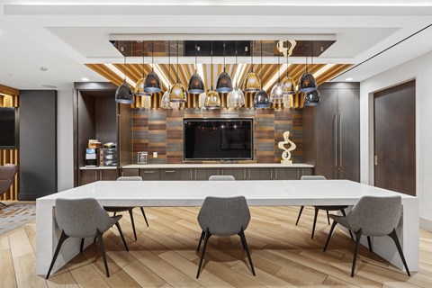 Community gathering area with large table and pendant lighting at The Hayward on Mass Ave