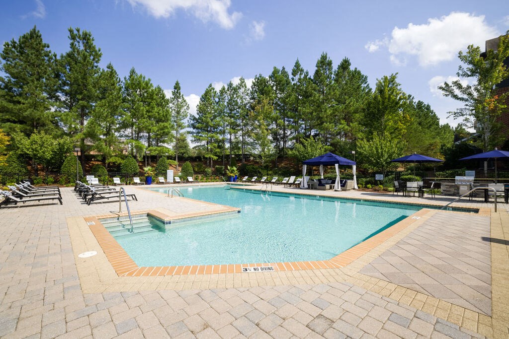 a swimming pool with chaise lounge chairs and trees in the background