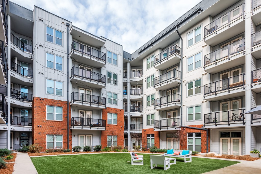 an exterior view of an apartment building with lawn and picnic tables