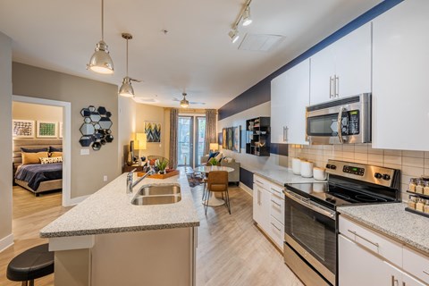 an open kitchen and living room with an island and a sink