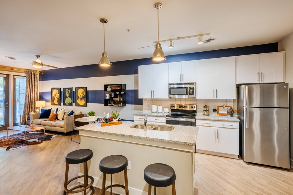 spacious kitchen with stainless steel appliances and island with three stools