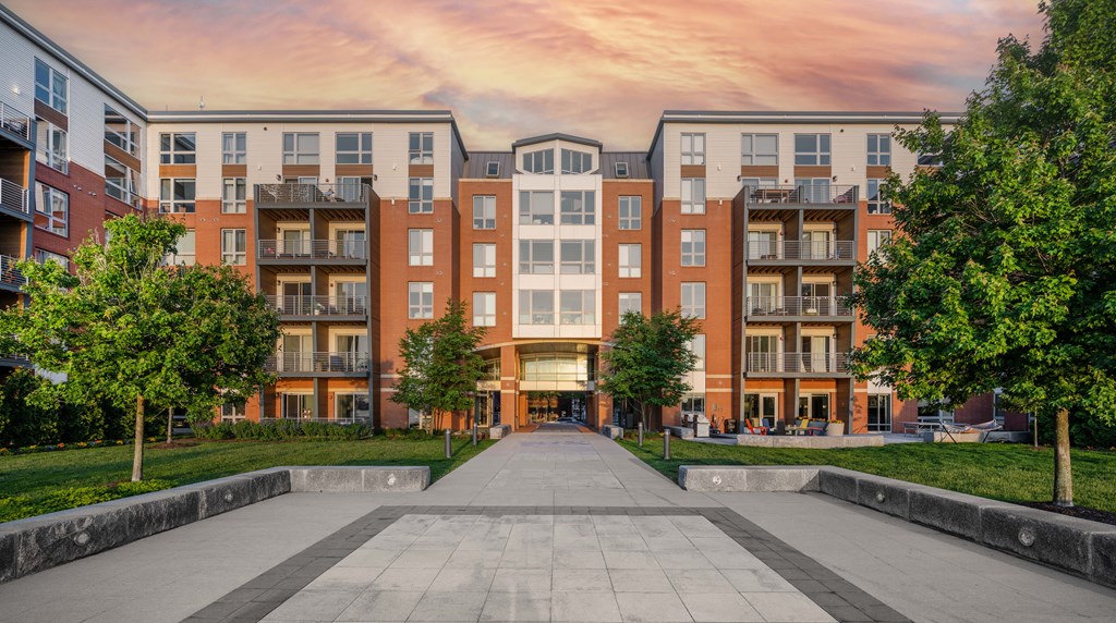 an exterior view of an apartment building with trees and a walkway