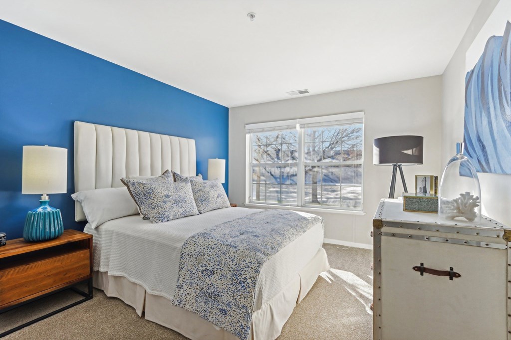A bedroom with a white bed and a blue accent wall.