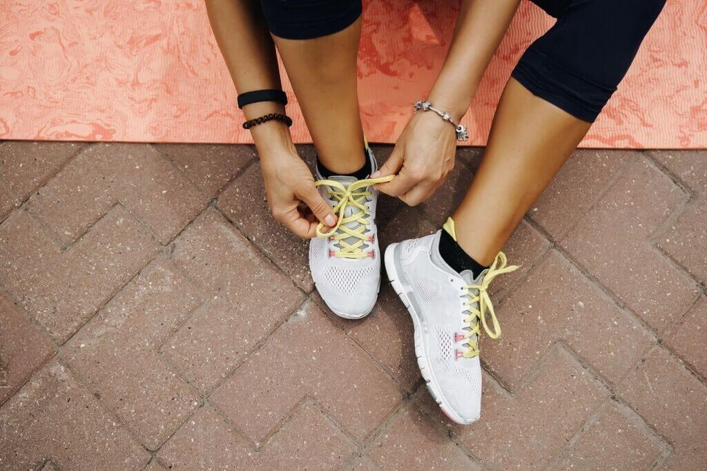 a woman tying her shoelaces on her sneakers