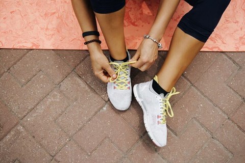 a woman tying her shoelaces on her sneakers