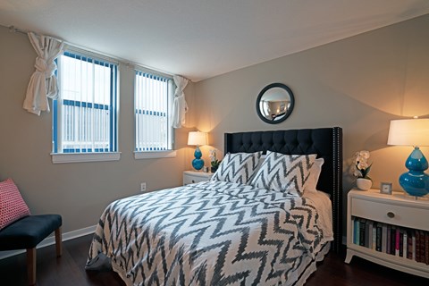 A bedroom with a black headboard and a patterned bedspread.