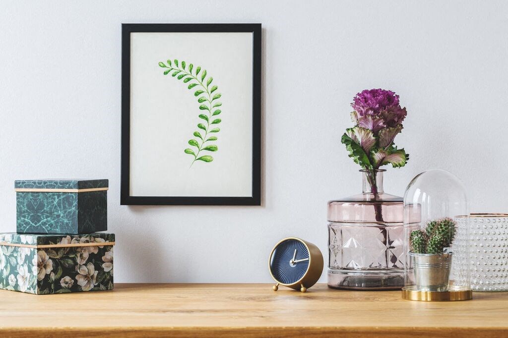 a picture frame on a table next to a clock and a vase of flowers