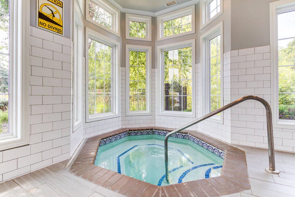 a soaking tub with a view of the trees outside the windows