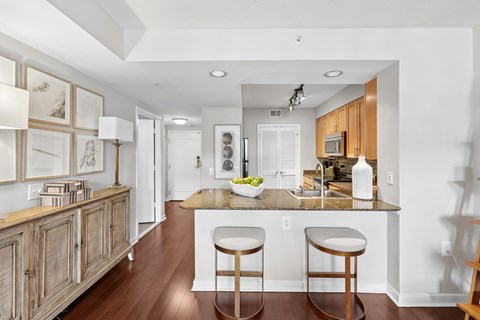 A kitchen with a bar stool in front of the counter.